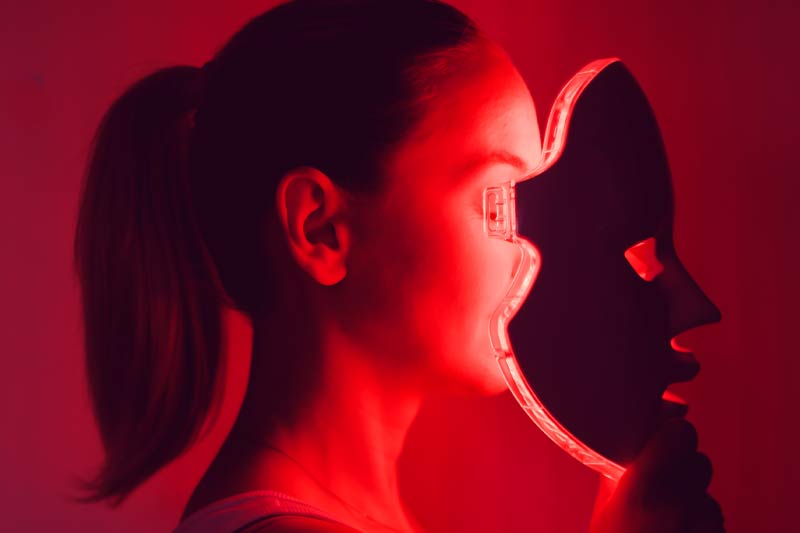 A girl applying a red light mask.