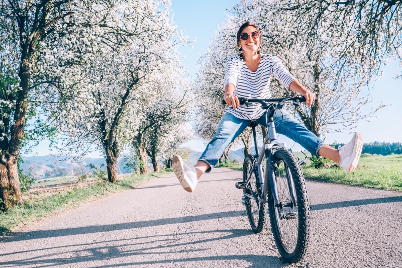 a happy woman on the bicycle in the spring